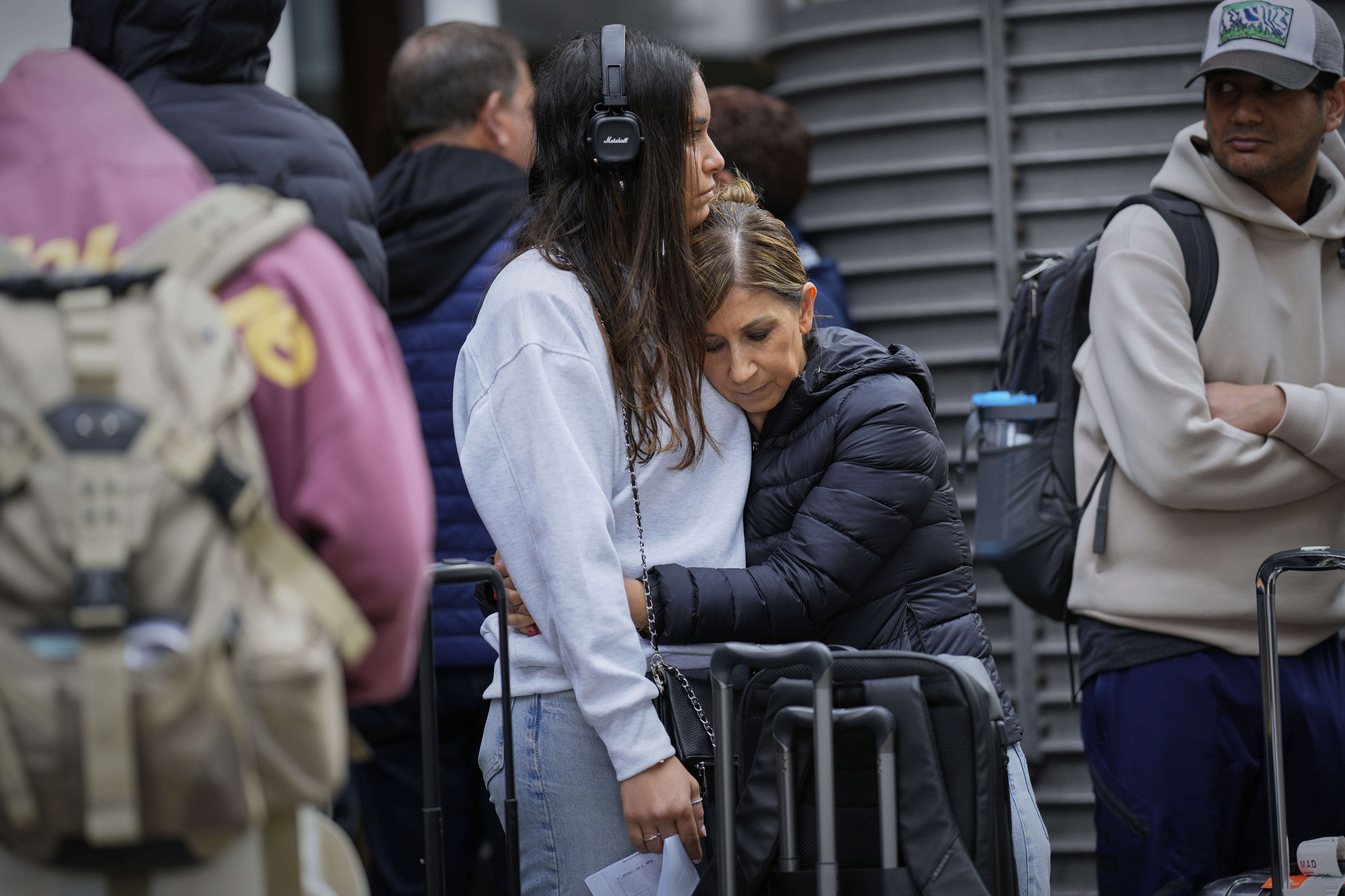 Passengers embrace at a Madrid train station following train delays due to cable theft.